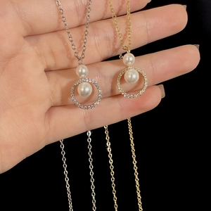 Elegante Perlenketten mit Zirkonia-Anhängern in Gold und Silber auf schwarzem Hintergrund
