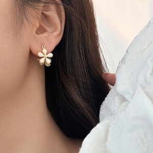 Elegant flower drop earrings with matte cream petals and golden core worn by model
