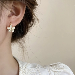 Close-up of elegant champagne flower earring with cat-eye luster on a model