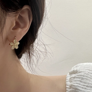 Elegant cream flower earring worn by a model showcasing delicate gold center accents
