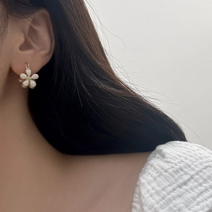Macro detail of elegant pearlescent flower earrings with gold-tone hardware and petals