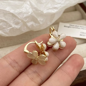Detailed close-up of elegant flower earrings with pearl finish and golden accents