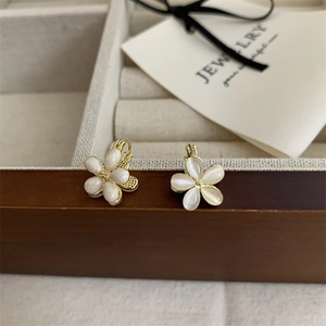 Close-up of elegant white petal flower earrings with gold trim on jewelry gift box