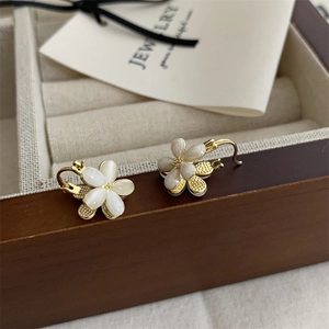 Detail of elegant gold flower earrings with cat-eye petals on a wooden jewelry box