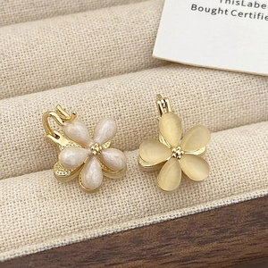 Macro shot of gold floral earrings with pearl white and amber yellow petals on velvet