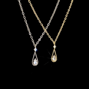 Detail view of gold and silver teardrop pendants with pear-shaped zircon stones