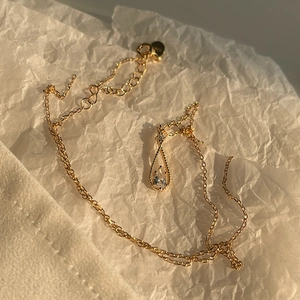 Close-up of gold pear-cut zircon teardrop pendant with intricate metal beadwork detailing