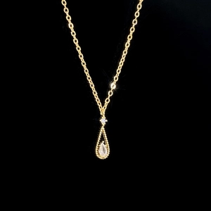 Close-up of gold water drop pendant with zircon inlay and elegant beaded edge details