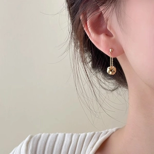 Minimalist gold tassel earrings with twisted knot pendants shown on a model