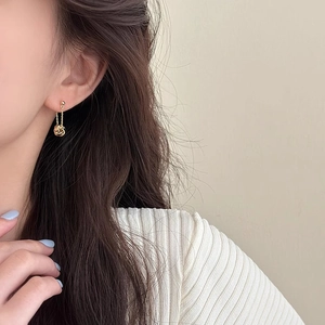 Detail of gold spiral twist tassel earrings with beaded studs and delicate chain on model