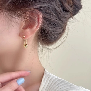 Detail of elegant gold tassel drop earrings with a stylish knotted circle pendant design