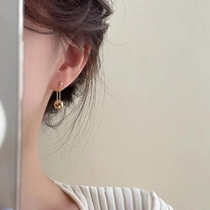 Close-up of a gold-plated knotted ball tassel earring worn on a model for a refined look