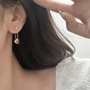 Detail of gold-plated spiral knot drop earrings worn by a model for an elegant look