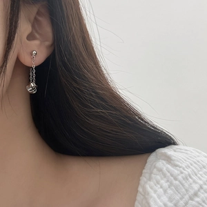 Close-up of geometric spiral twist tassel earrings in silver finish on a model
