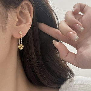 Detail of elegant gold tassel earrings with interlocking rings on a female model