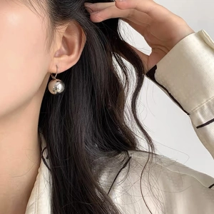 Minimalist silver spherical ball drop earrings for women shown worn on a model