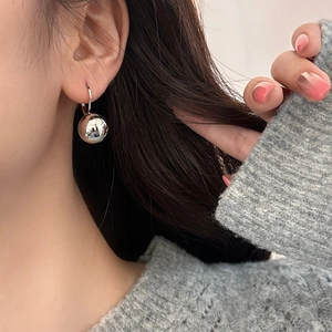 Detail view of silver spherical earrings with high polish finish worn by a model