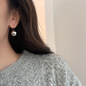 Close-up of minimalist silver ball drop earrings with mirror finish on female model