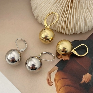 Macro shot of minimalist polished gold and silver ball earrings with lever-back closures