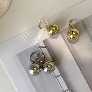 Close-up of gold and silver leverback ball earrings with a mirror polished finish