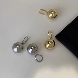Polished gold and silver ball lever-back earrings displayed on a white surface