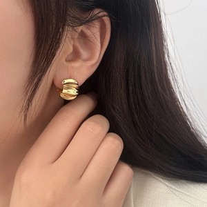 Detail view of gold textured hoop earrings featuring unique horizontal wave patterns