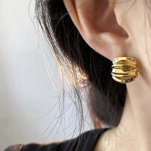 Detail of gold textured twist earring with high-polished croissant style design