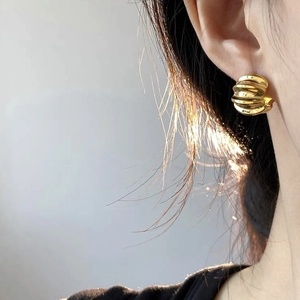 Detailed view of golden croissant hoop earrings with a polished ribbed metal texture