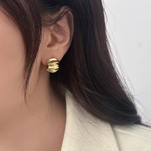 Close-up of gold wave-textured hoop earrings with a high-shine liquid metal finish