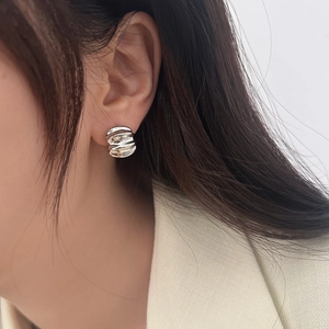 Close-up of irregular wave textured silver earrings worn by model for an elegant look