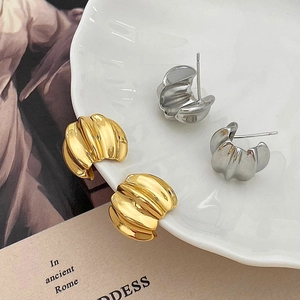 Detailed view of gold and silver textured hoop earrings on a vintage book and plate