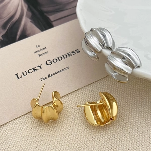 Detail showing wavy textured C-shape hoop earrings in gold and silver finishes