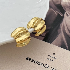 Detailed view of gold wrinkled hoop earrings displayed on a vintage ceramic dish