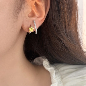 Close-up of star-shaped zircon earring and silver curved bar stud on ear for women