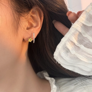 Close-up of a gold star earring and crystal bar stud on model ear for a delicate look