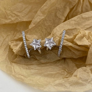 Detailed view of silver star earrings with micro-set zircons on textured paper
