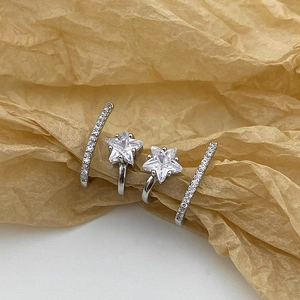 Elegant silver star earrings with white zircon crystals on a textured paper background