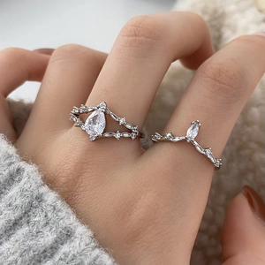 Macro shot of silver crown ring with pear-shaped stone and V-shaped band on finger