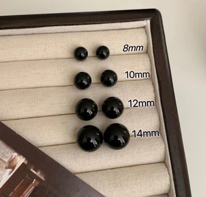Detailed comparison of 8mm to 14mm black pearl stud earrings on a velvet display tray