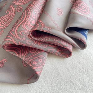 Nahaufnahme eines Paisley-Seidenschals mit grau-rosa Mustern und Satinschimmer
