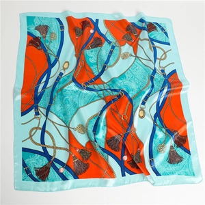 Détail d'un foulard en soie avec chaîne dorée, pompons et motifs paisley élégants