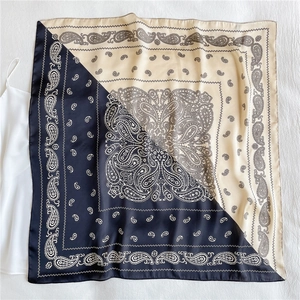 Detail eines quadratischen Seidenschals mit schwarzem und beige Paisleymuster
