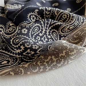 Detailansicht eines Seidentuchs mit Paisleymuster in Schwarz-Grau und weicher Stoffstruktur