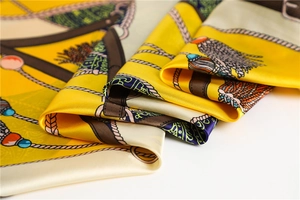 Vue détaillée d'un foulard en satin avec motifs de chaînes dorées et de pompons