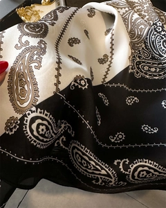 Detailansicht des Seidenschals mit schwarz-weißem Paisley-Muster und glänzender Textur