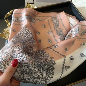 Detailaufnahme des rosa-weißen Seidenschals mit Paisleymuster und elegantem Satin-Glanz