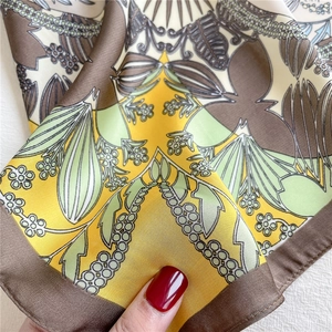 Close-up of a floral print silk square scarf showing soft texture and rolled edges