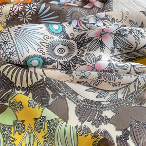 Close-up of silk-like square scarf featuring retro floral print and soft fabric texture