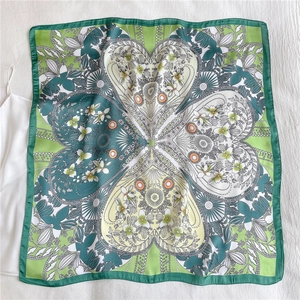 Flat lay of floral silk scarf featuring symmetrical green heart-shaped flower patterns