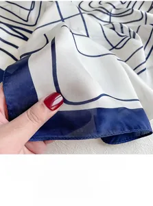 Close-up of geometric pattern silk scarf showing navy blue lines and detailed stitching